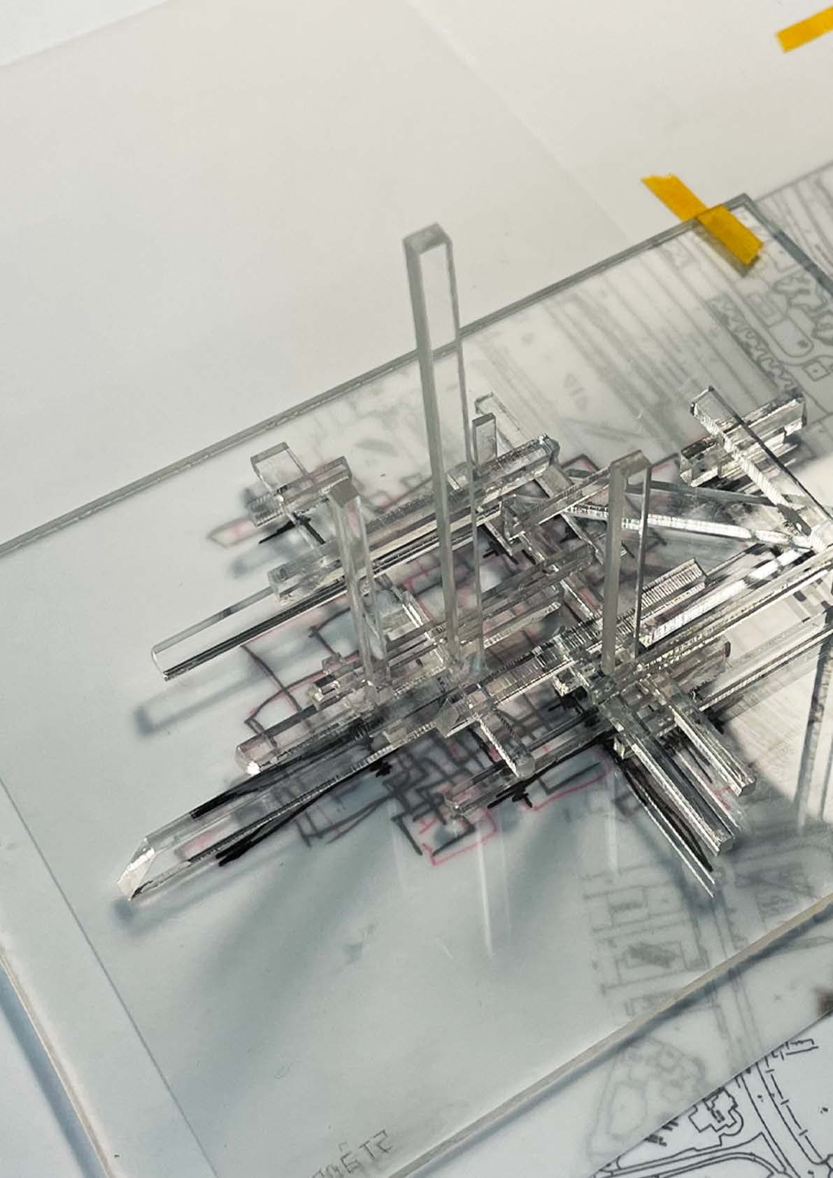SSP-2 model from above — clear acrylic risers and crossing service bars stacked over layered plans of the district