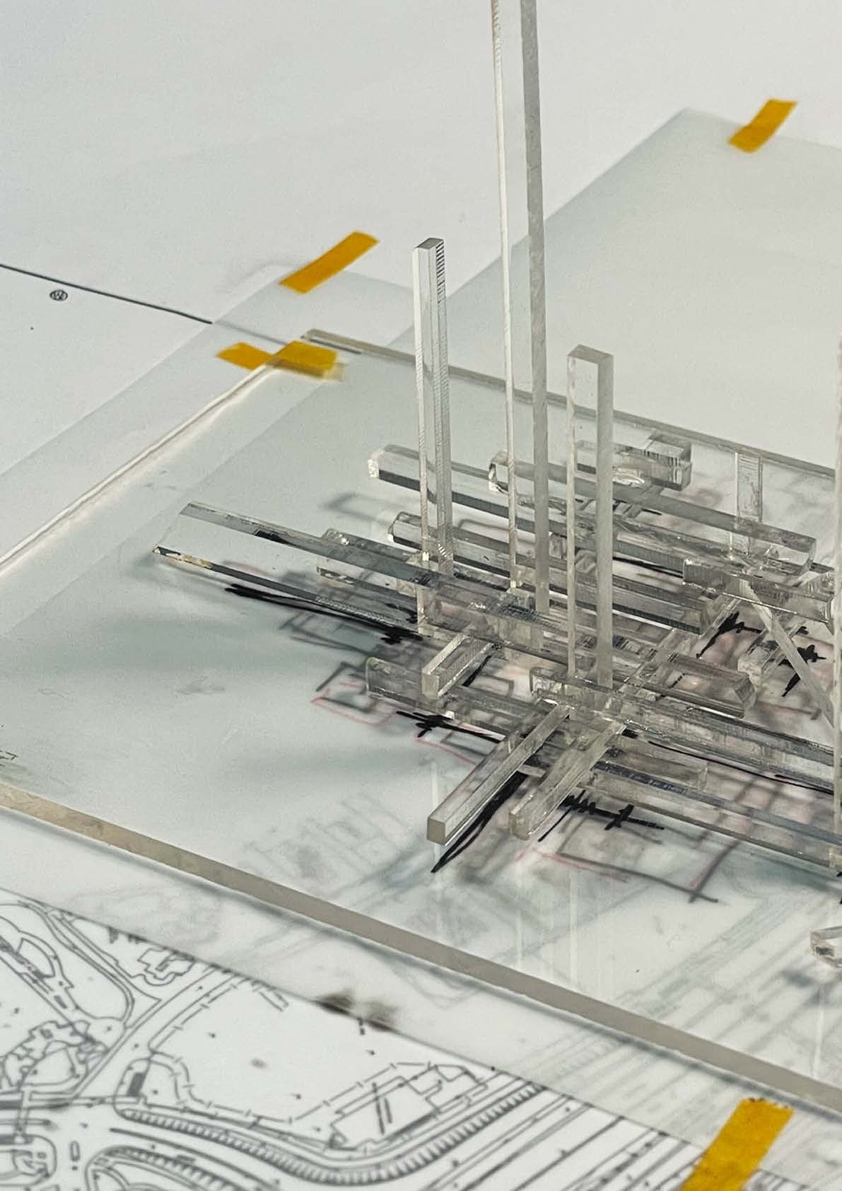 SSP-2 model across the mapping field — vertical shafts rising from the buried grid, taped plan sheets receding beneath the acrylic plates